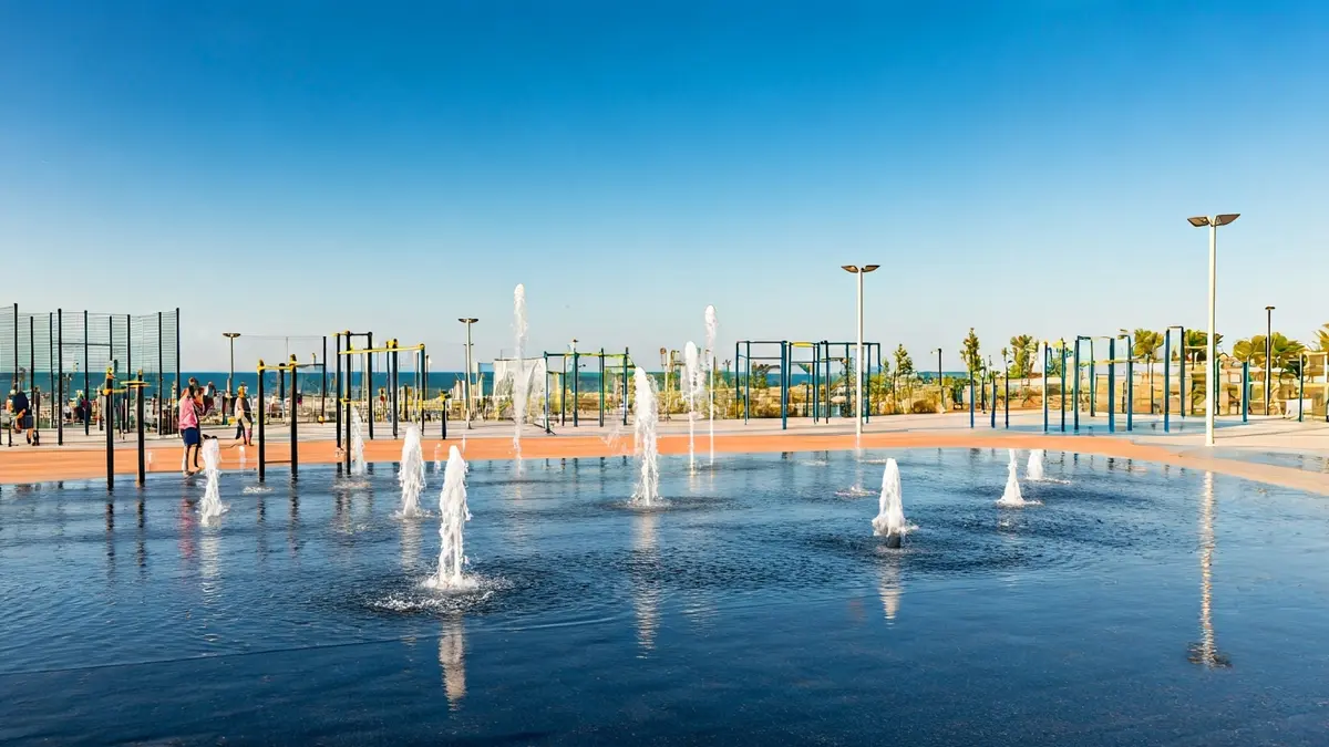 Imagen de un parque temático moderno con diversas instalaciones deportivas y de ocio, incluyendo una fuente interactiva y zonas verdes.
