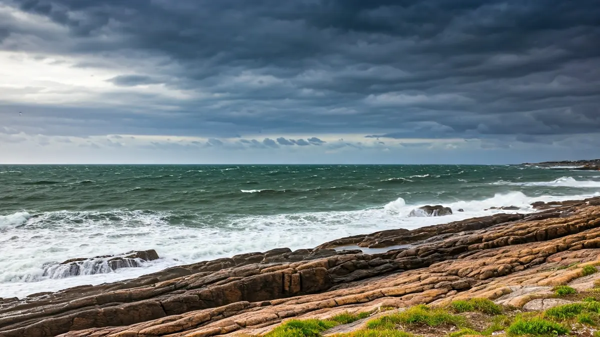 Imagen genérica de oleaje intenso en una costa rocosa bajo un cielo tormentoso.