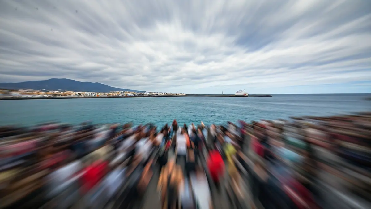 Imagen genérica de una costa con un puerto a lo lejos, bajo un cielo nublado, sugiriendo un punto de entrada y salida.