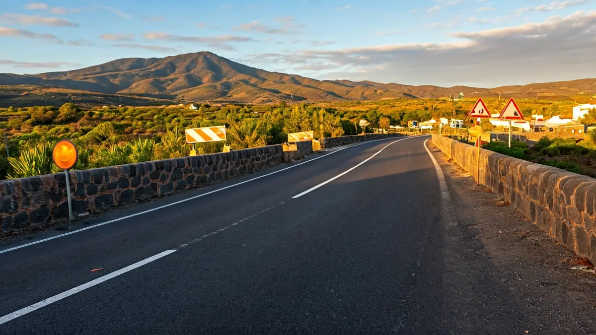 Imagen de un puente de piedra antiguo con obras de ensanche y señalización de cierre de carretera en un entorno rural canario.