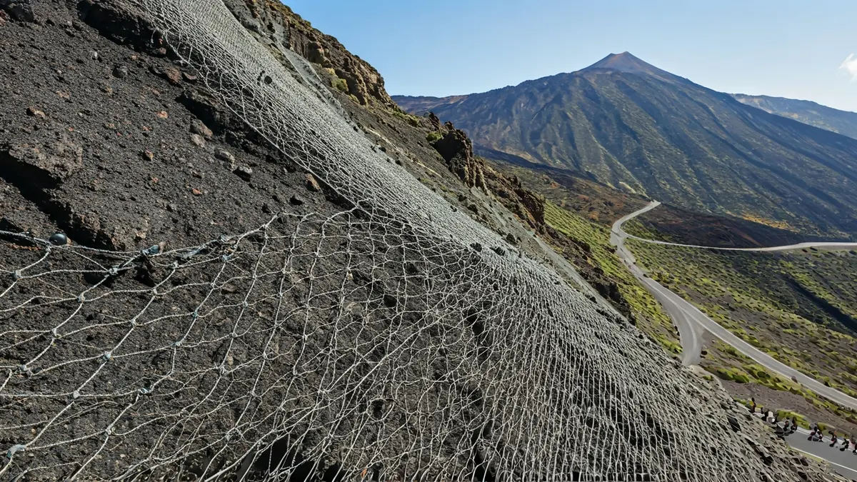 Image of a rockfall containment net on a slope next to a road in La Palma.