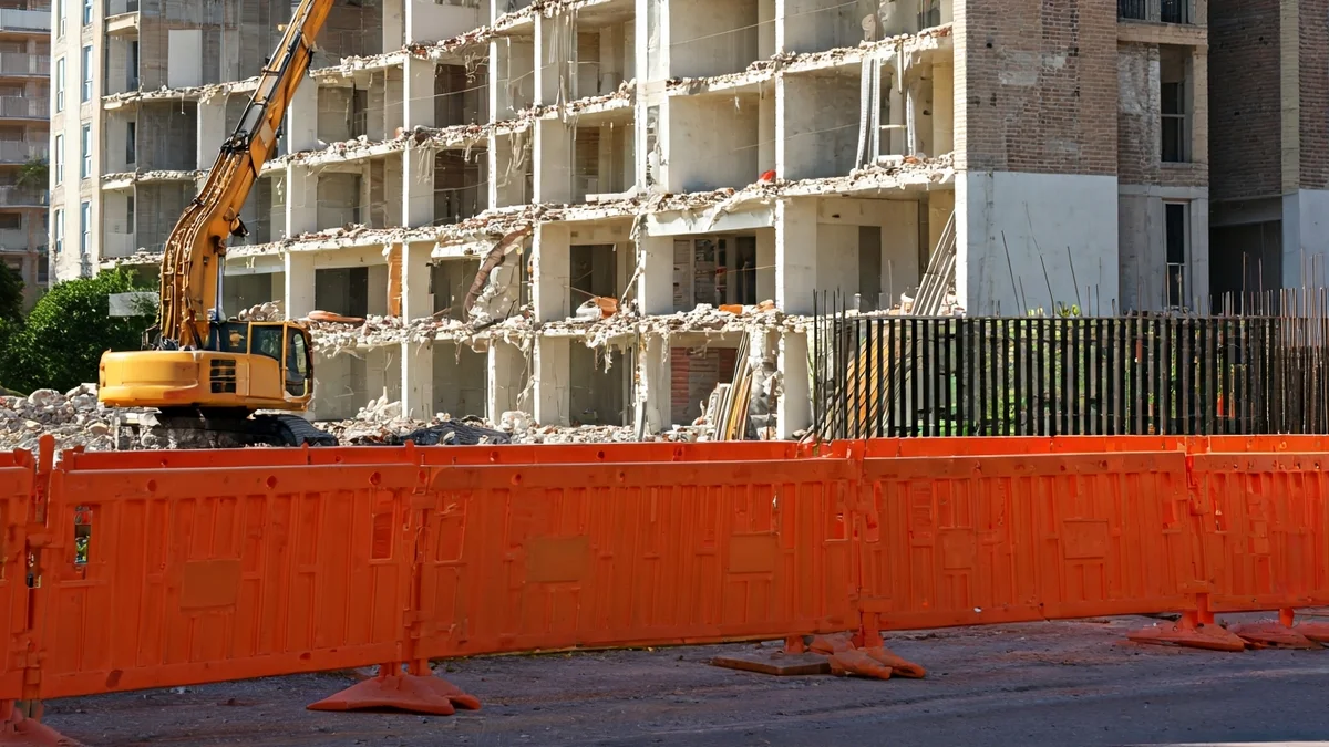 Imagen de un solar en construcción con barreras de seguridad y un edificio parcialmente demolido.
