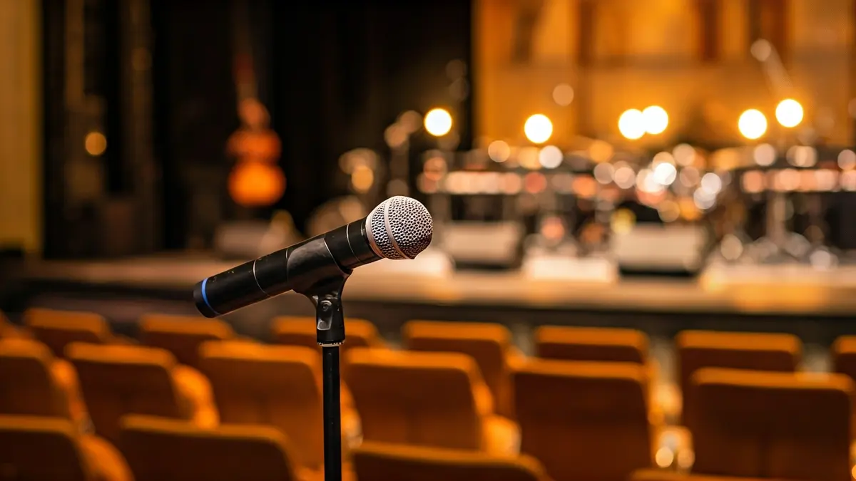Imagen genérica de un escenario de concierto con un micrófono y luces cálidas.