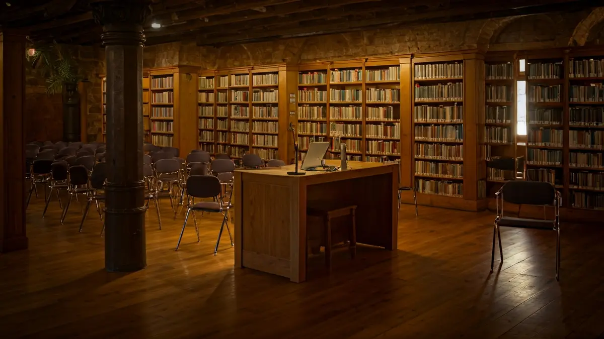 Imagen genérica de un interior de biblioteca con estanterías de madera y un podio con micrófono, iluminado con luz cálida.