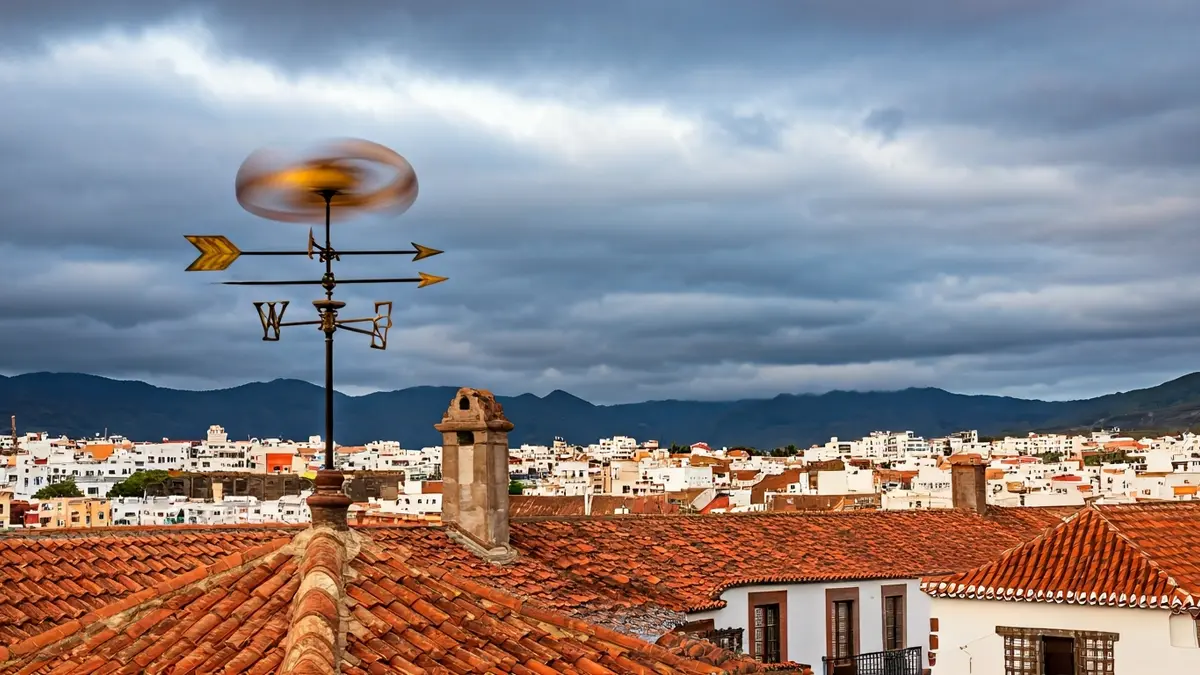 Imagen genérica de una veleta girando con fuerza en un tejado bajo un cielo nublado, simbolizando el viento.