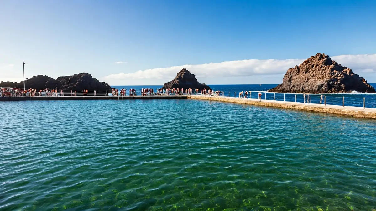 Imagen de una piscina natural de agua de mar en la costa canaria, con rocas volcánicas y el océano de fondo.