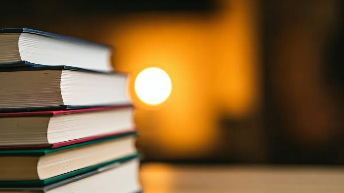 Imagen genérica de libros apilados en una mesa, con iluminación cálida.