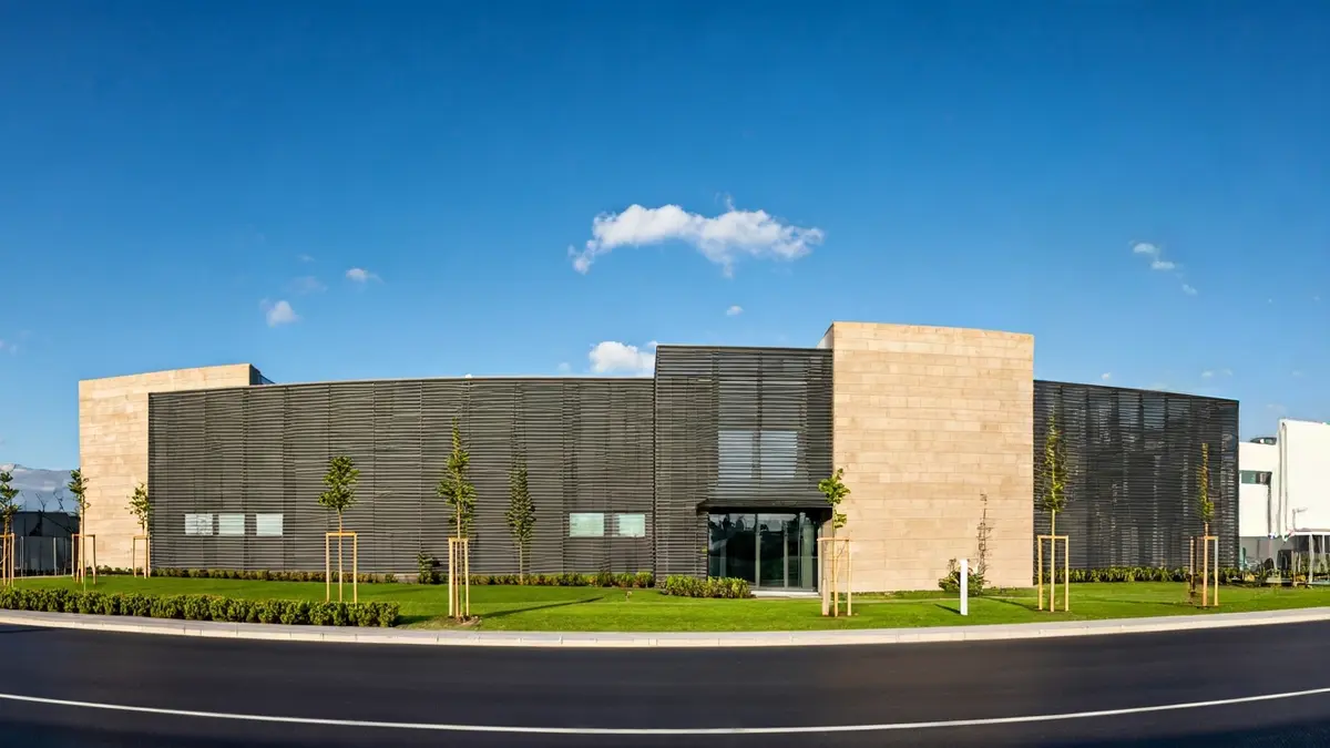 Fachada de un edificio industrial con colores neutros y vegetación, bajo el sol de Canarias.