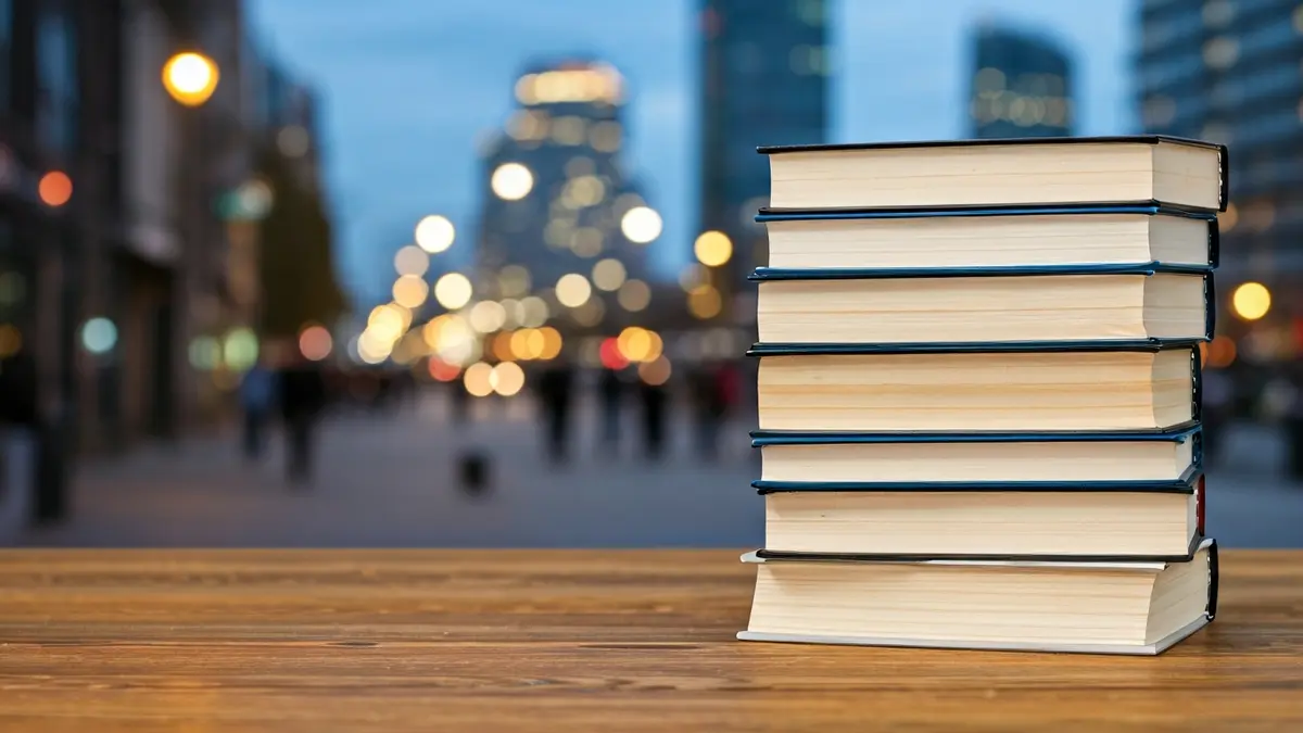 Imagen genérica de libros sobre una mesa con un fondo urbano borroso, simbolizando la cultura y el desarrollo.