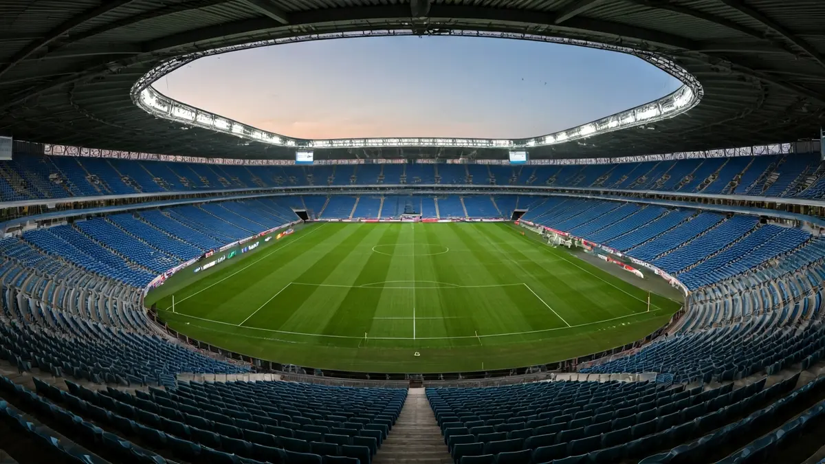 Imagen genérica de un estadio vacío, con asientos y césped, iluminado por la luz de la tarde.