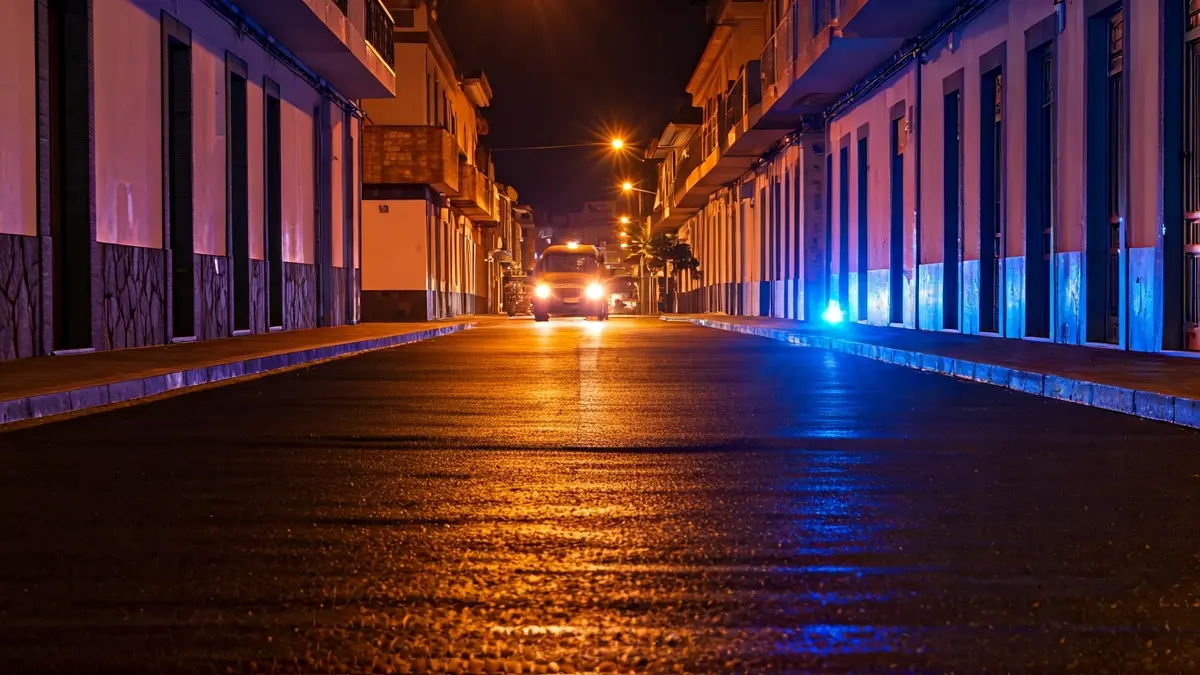 Imagen genérica de luces de emergencia policiales reflejadas en el asfalto mojado de noche.