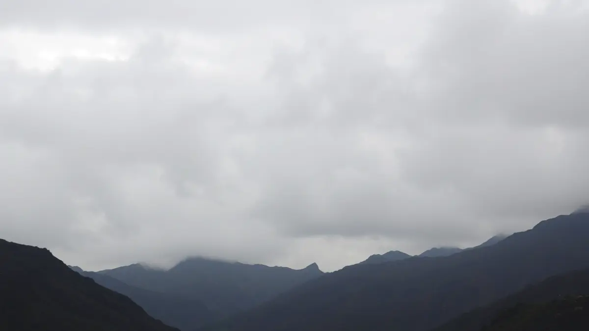 Generic image of an overcast sky with some high clouds over a mountainous landscape in the Canary Islands, with light rain.