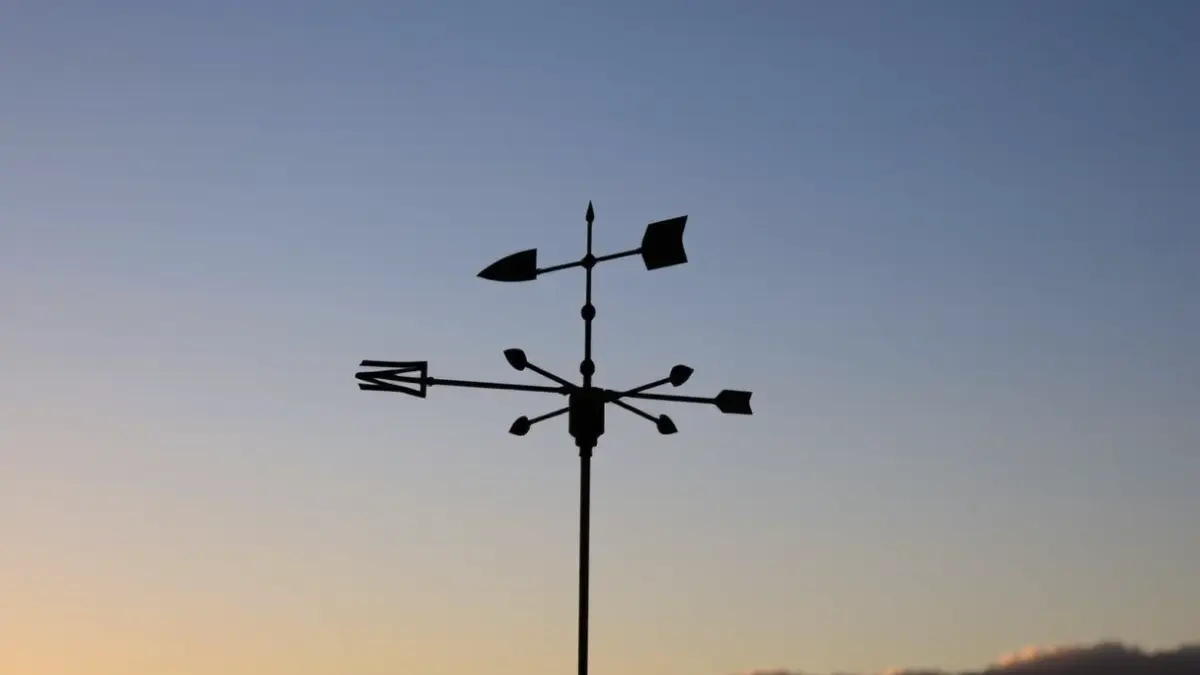 Generic image of a weather vane at dawn, with scattered clouds on the horizon.