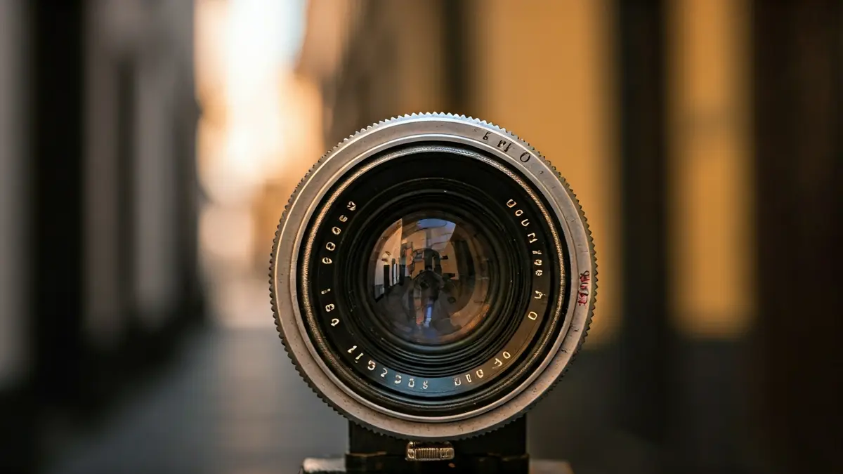 Imagen de una lente de cámara antigua, reflejando una escena callejera borrosa.
