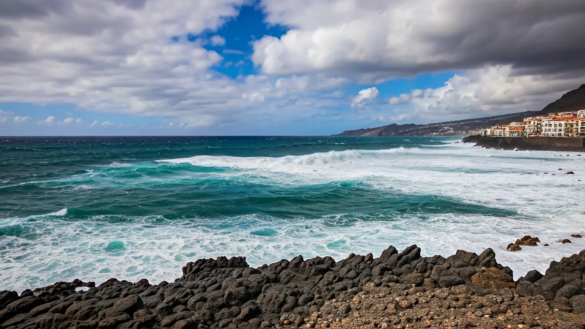 Image of large waves breaking on the Tenerife coast under a cloudy sky.