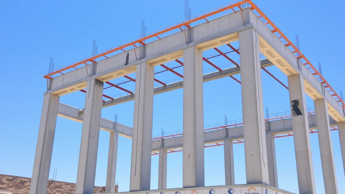 Concrete structure of a building under construction against a blue sky.