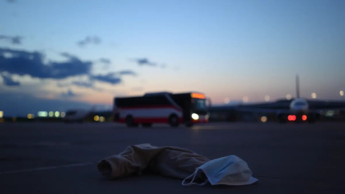 Image of personal protective equipment (PPE) and a face mask on an airport tarmac, after a health operation.