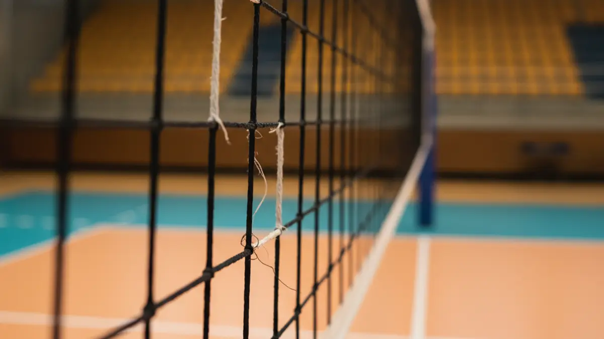 Imagen genérica de una red de voleibol en una cancha iluminada.