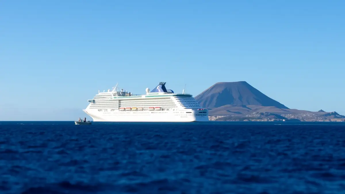 Imagen de un crucero fondeado en la costa de Tenerife, con una embarcación acercándose.