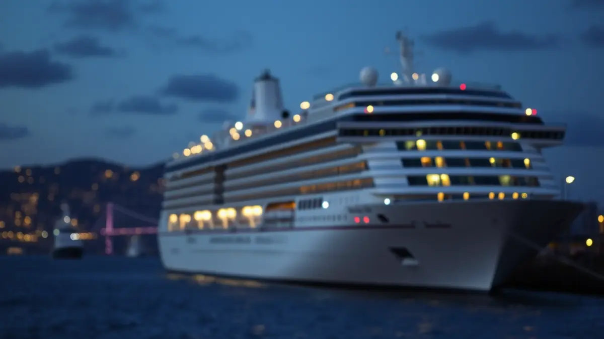 Imagen genérica de un crucero anclado en un puerto al atardecer, con luces de la ciudad borrosas al fondo.