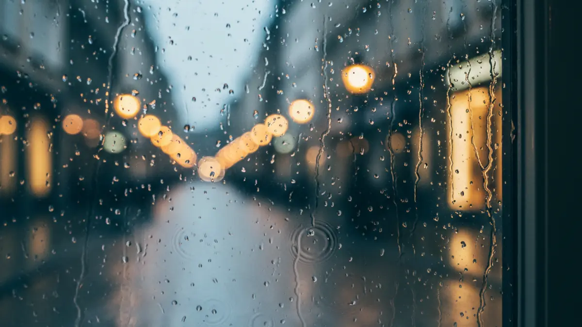 Imagen genérica de gotas de lluvia en un cristal, con una calle borrosa al fondo.