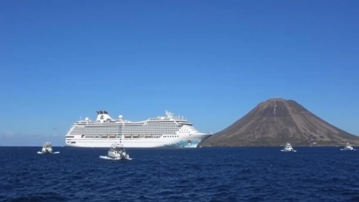 Imagen de un crucero fondeado cerca de la costa de Tenerife, con embarcaciones más pequeñas alrededor.