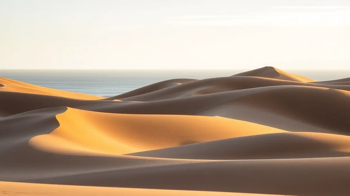Paisaje de las Dunas de Maspalomas en Gran Canaria, con dunas de arena y el océano al fondo.