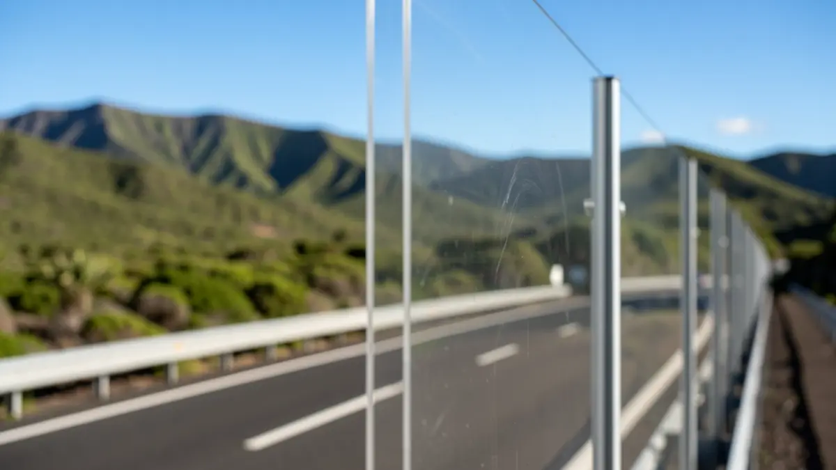 Pantalla acústica transparente en la autopista TF-1 de Tenerife, con vegetación volcánica al fondo.