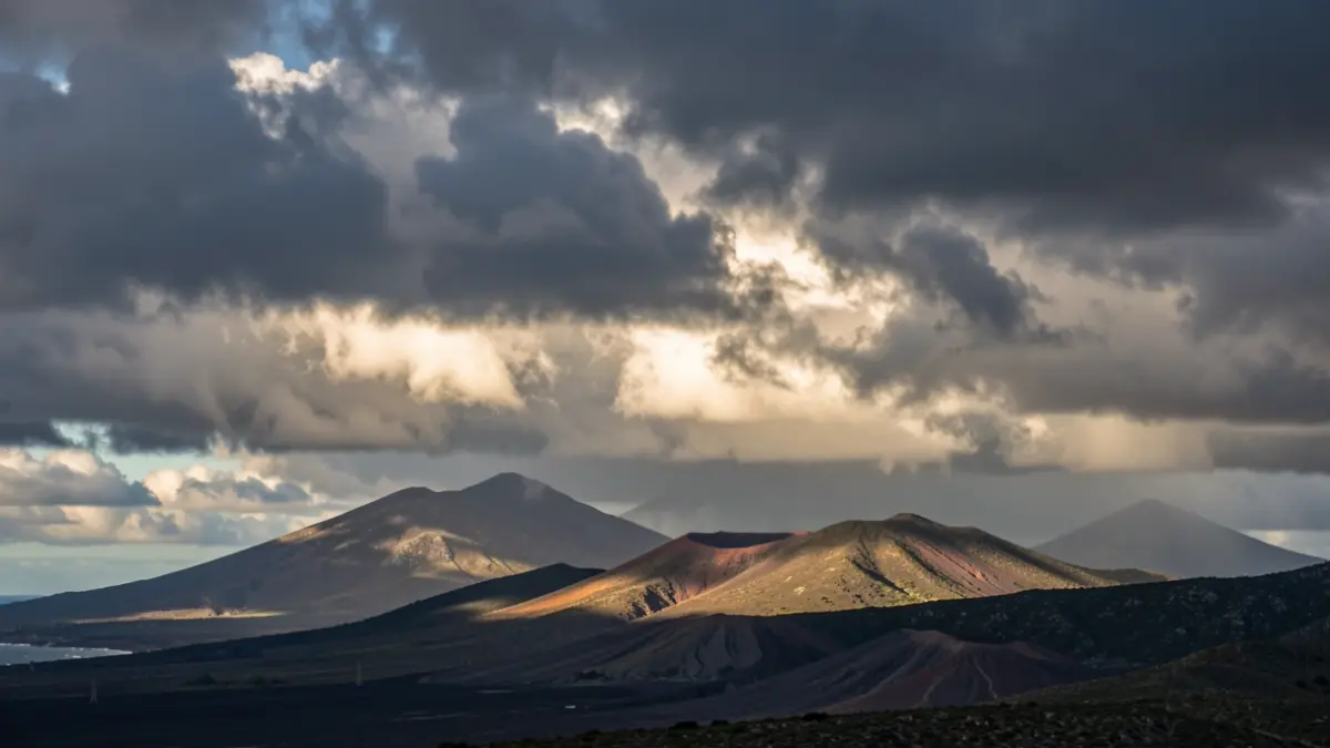 Threatening sky with rain clouds and patches of sun over a volcanic landscape in the Canary Islands.