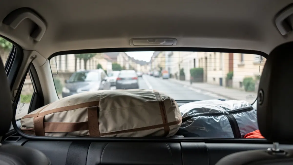Imagen de equipaje mal colocado en la bandeja trasera de un coche, obstruyendo la visibilidad.