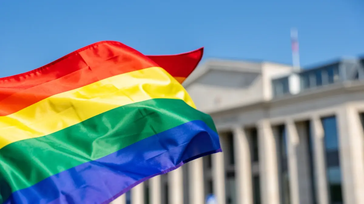Rainbow flag unfurled in front of a town hall.