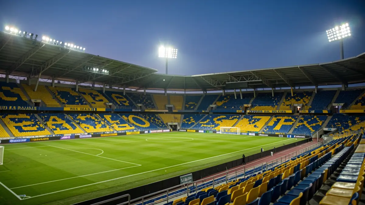 Generic image of a football stadium at dusk, with illuminated pitch and empty seats.