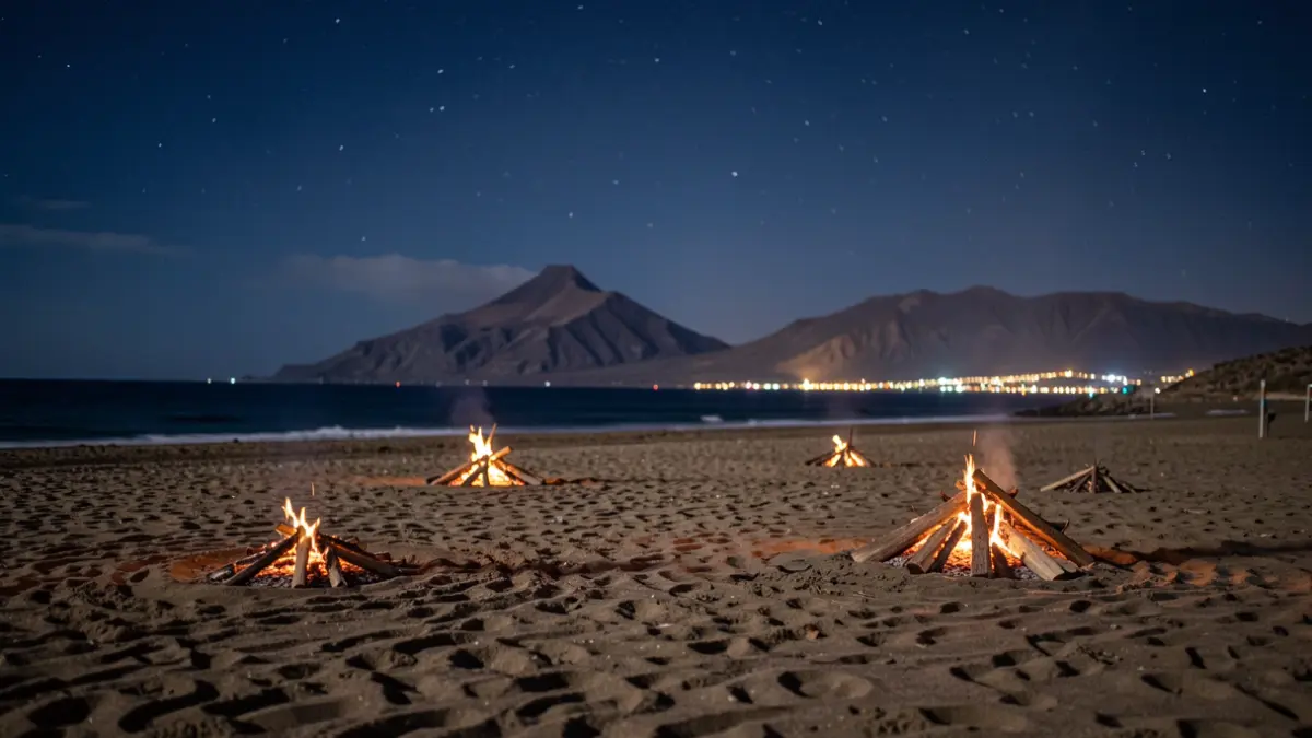 Generic image of a Canary Islands beach at night, with unlit bonfires and volcanic landscape in the background.
