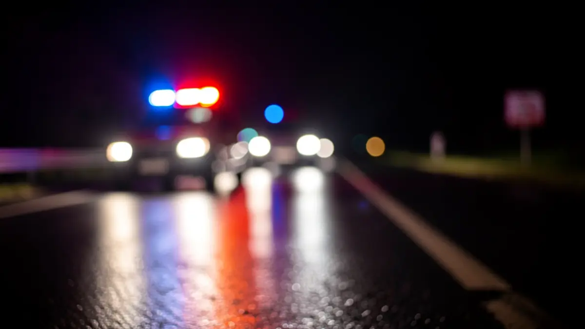 Generic image of emergency lights reflecting on wet asphalt at night.