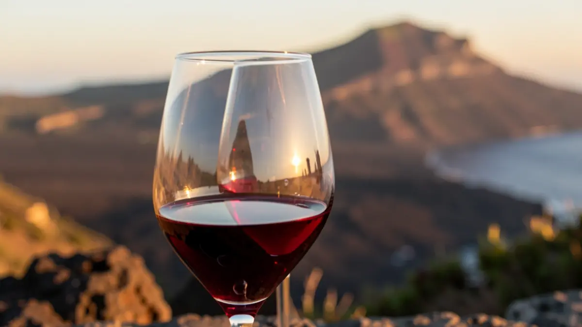 Close-up of a glass of red wine with a Canary Islands volcanic landscape in the background.