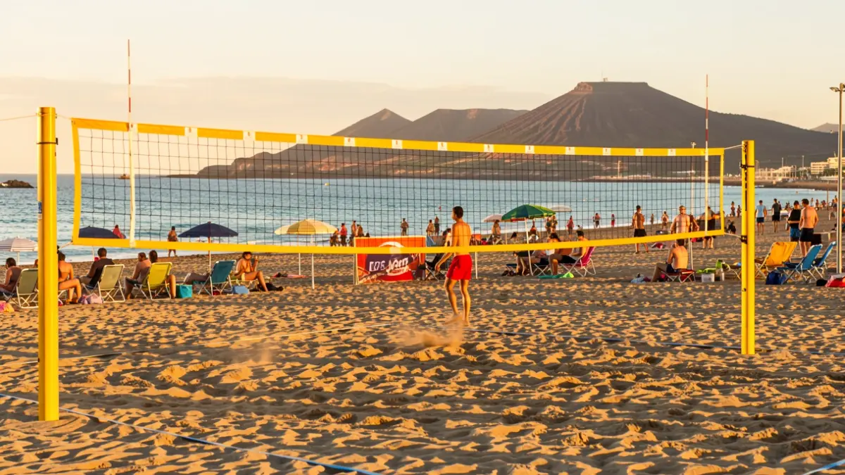 Pista de vóley playa en la Playa de Las Canteras, Gran Canaria, con el mar y el paisaje volcánico al fondo.