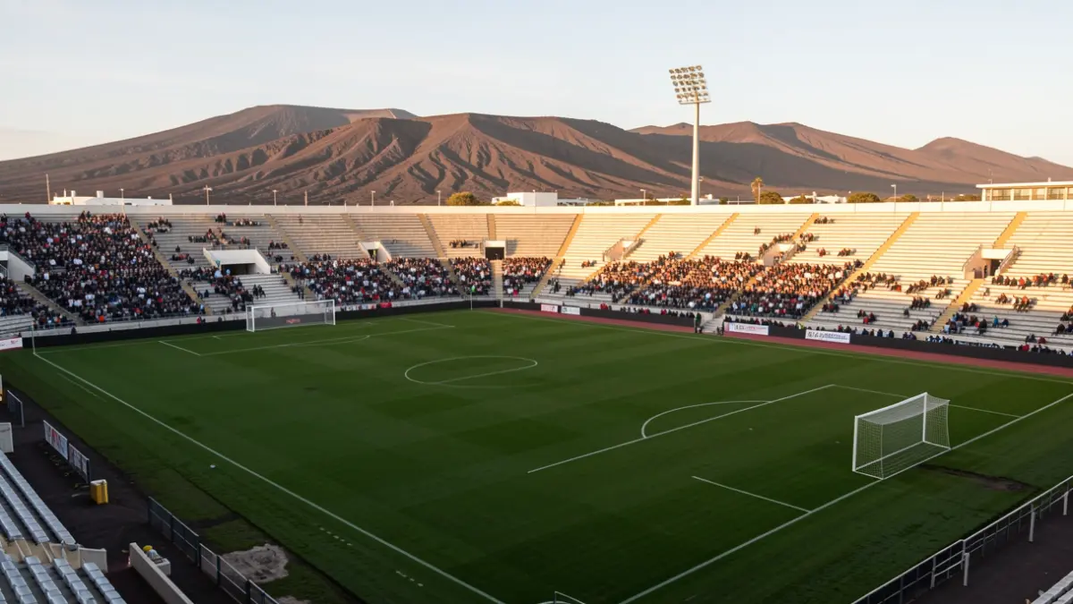 Imagen genérica de un estadio de fútbol vacío en Fuerteventura con paisaje volcánico al fondo.