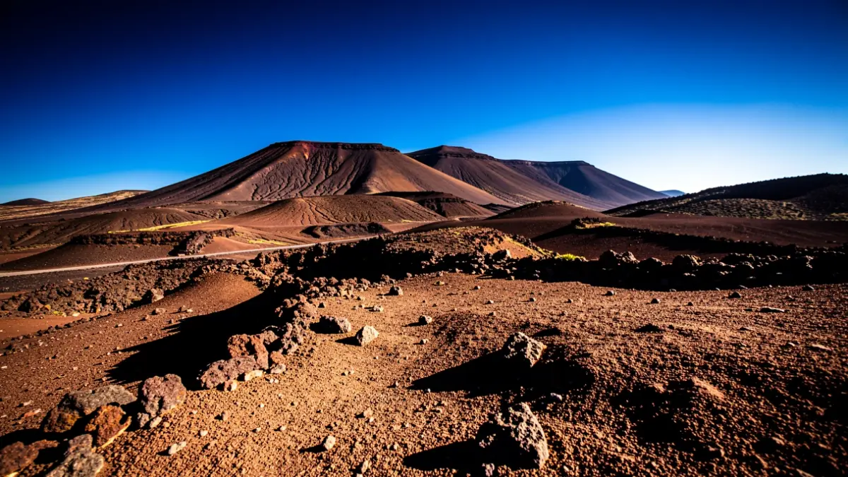 Paisaje volcánico de Tenerife bajo un sol intenso con sombras marcadas.