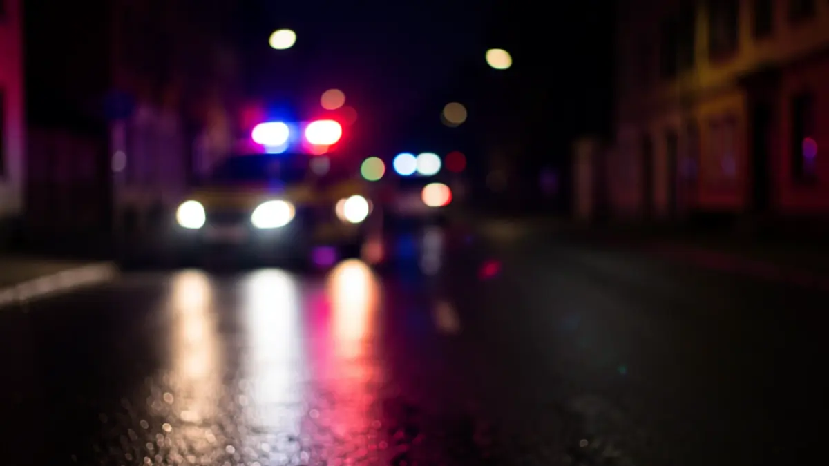 Imagen genérica de luces de emergencia policiales reflejando en asfalto mojado por la noche.