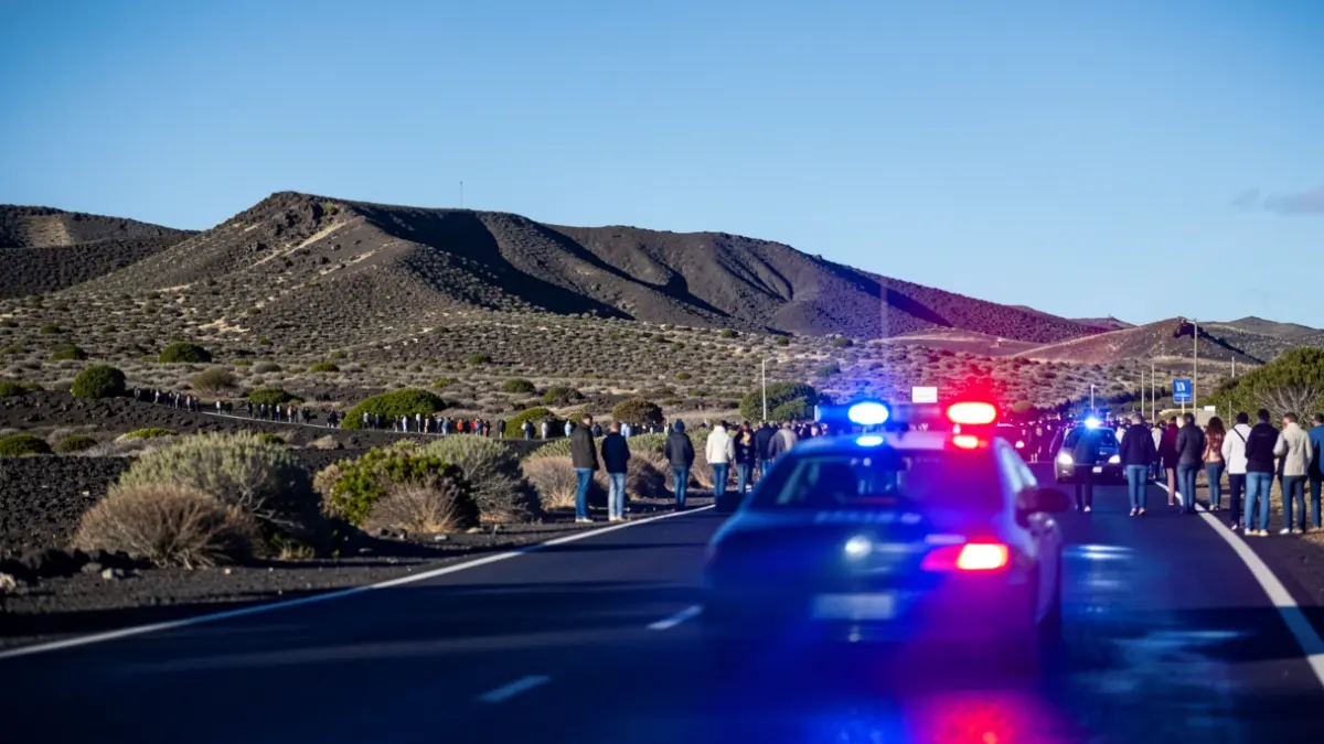 Imagen genérica de luces de emergencia policiales reflejándose en asfalto mojado con paisaje volcánico de Canarias al fondo.