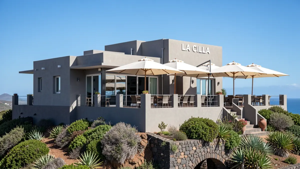 Exterior of the 'La Cilla' restaurant-mirador in Artenara, Gran Canaria, featuring neutral tones and umbrellas on the terrace.