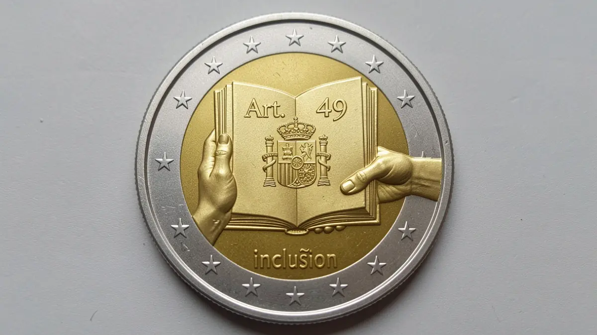 Close-up of a 2 euro commemorative coin featuring Article 49 of the Constitution and the Spanish shield.