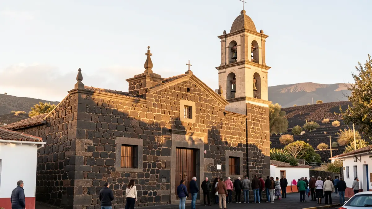 Fachada de la Iglesia de Alojera con su campanario, bajo la luz del sol de la tarde.