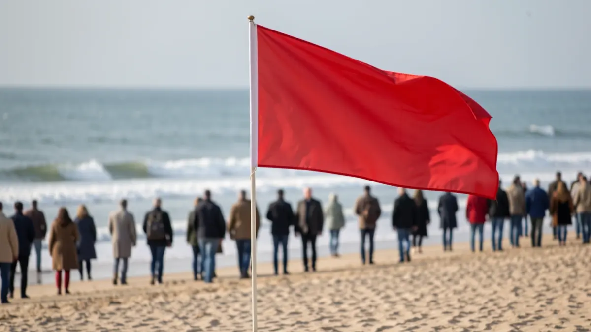 Red flag waving on a beach, indicating a swimming ban due to pollution.