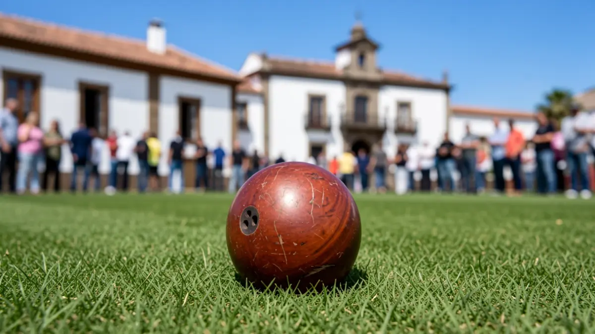 Bola canaria sobre césped con arquitectura tradicional canaria al fondo.