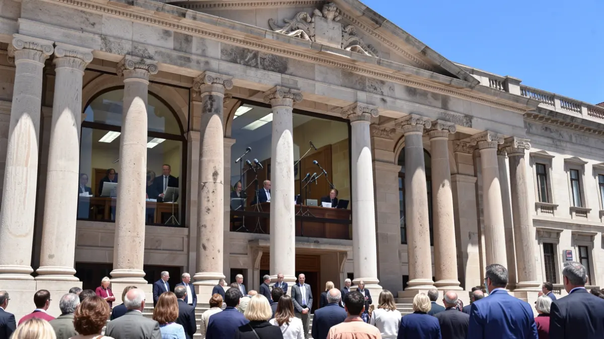 Fachada del Parlamento de Canarias con micrófonos visibles en el interior.