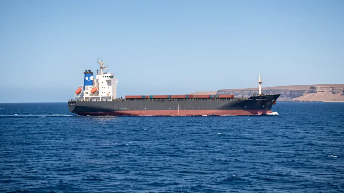 Imagen genérica de un barco de carga navegando en el mar con la costa de Fuerteventura al fondo.